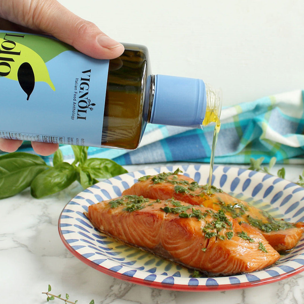 Vignoli Nocellara del Belice Monocultivar Extra Virgin Olive Oil front of 16.9oz bottle being poured over baked salmon