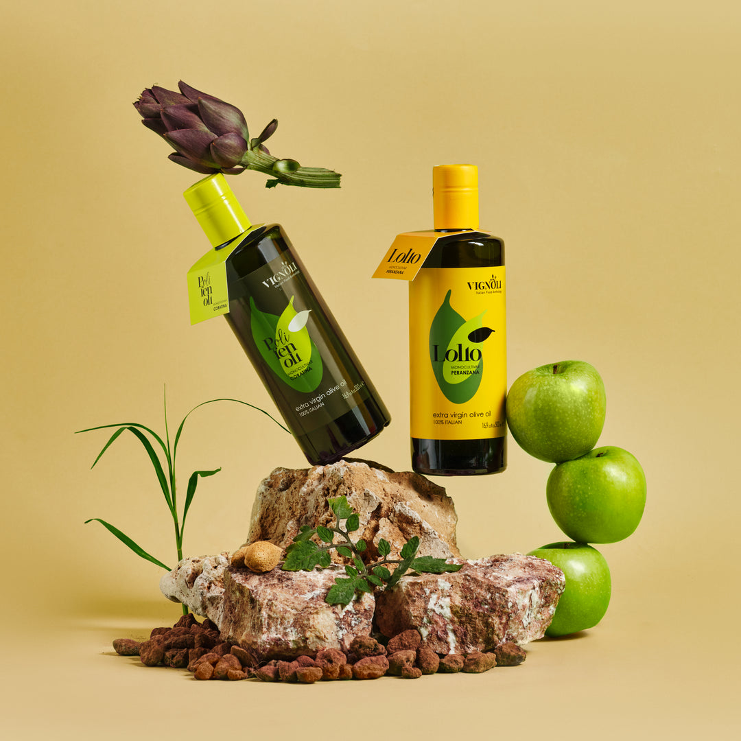 Coratina Monocultivar Extra Virgin Olive Oil front of 16.9oz bottle on rock with apples and artichoke