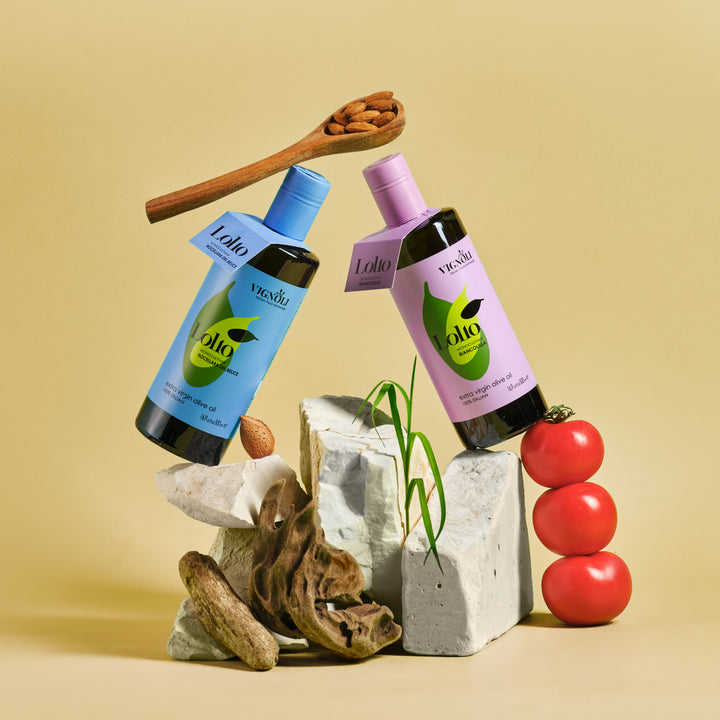 Biancolilla Monocultivar Extra Virgin Olive Oil front of 16.9fl oz bottle on rocks with tomatoes and nuts