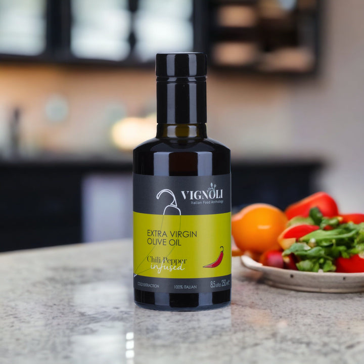 Chili Pepper Infused Extra Virgin Olive Oil front of 8.5oz bottle on table with vegetables in the background
