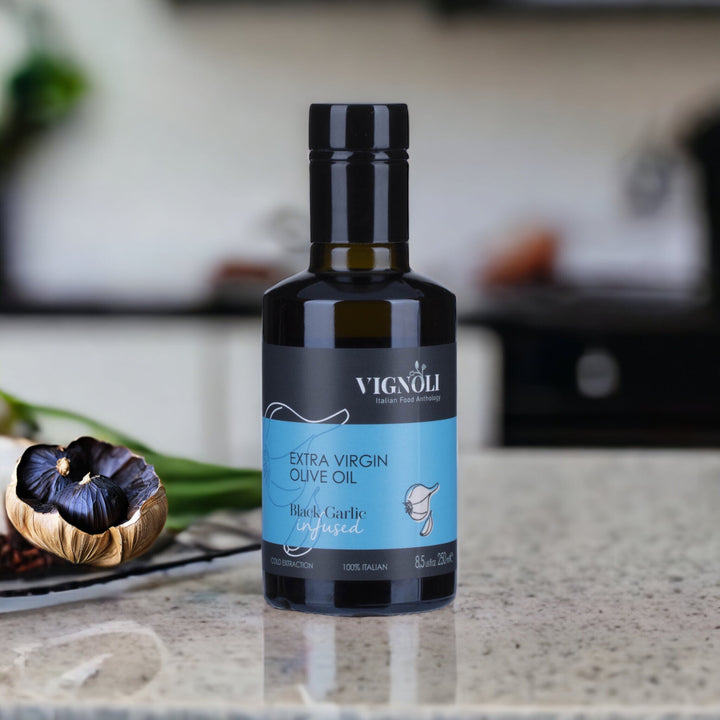 Black Garlic Infused Extra Virgin Olive Oil front of 8.5oz bottle on table with black garlic