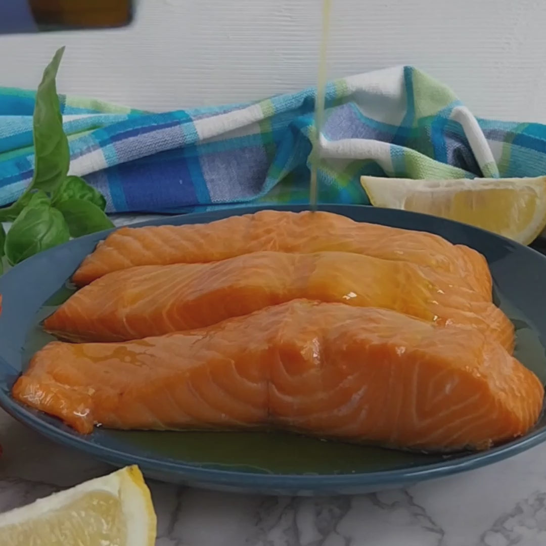 Vignoli Nocellara del Belice Monocultivar Extra Virgin Olive Oil front of 16.9oz bottle being poured over baked salmon