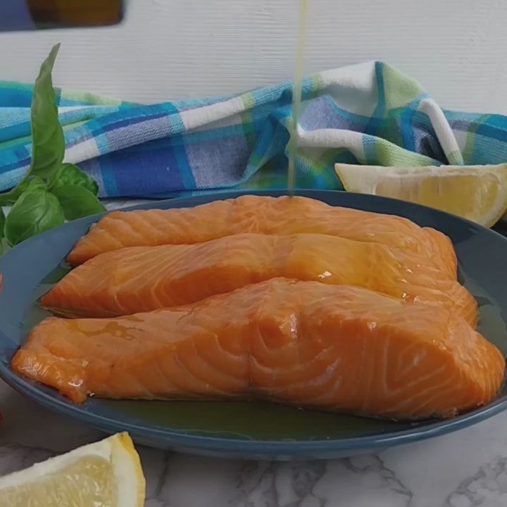 Vignoli Nocellara del Belice Monocultivar Extra Virgin Olive Oil front of 16.9oz bottle being poured over baked salmon