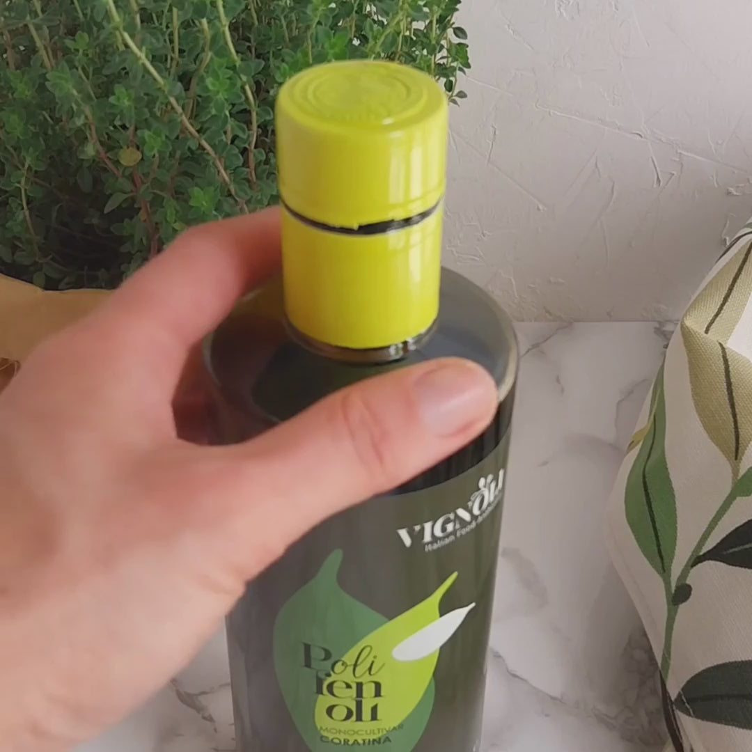 Coratina Monocultivar Extra Virgin Olive Oil front of 16.9oz bottle being opened and poured over grilled eggplant and tomato