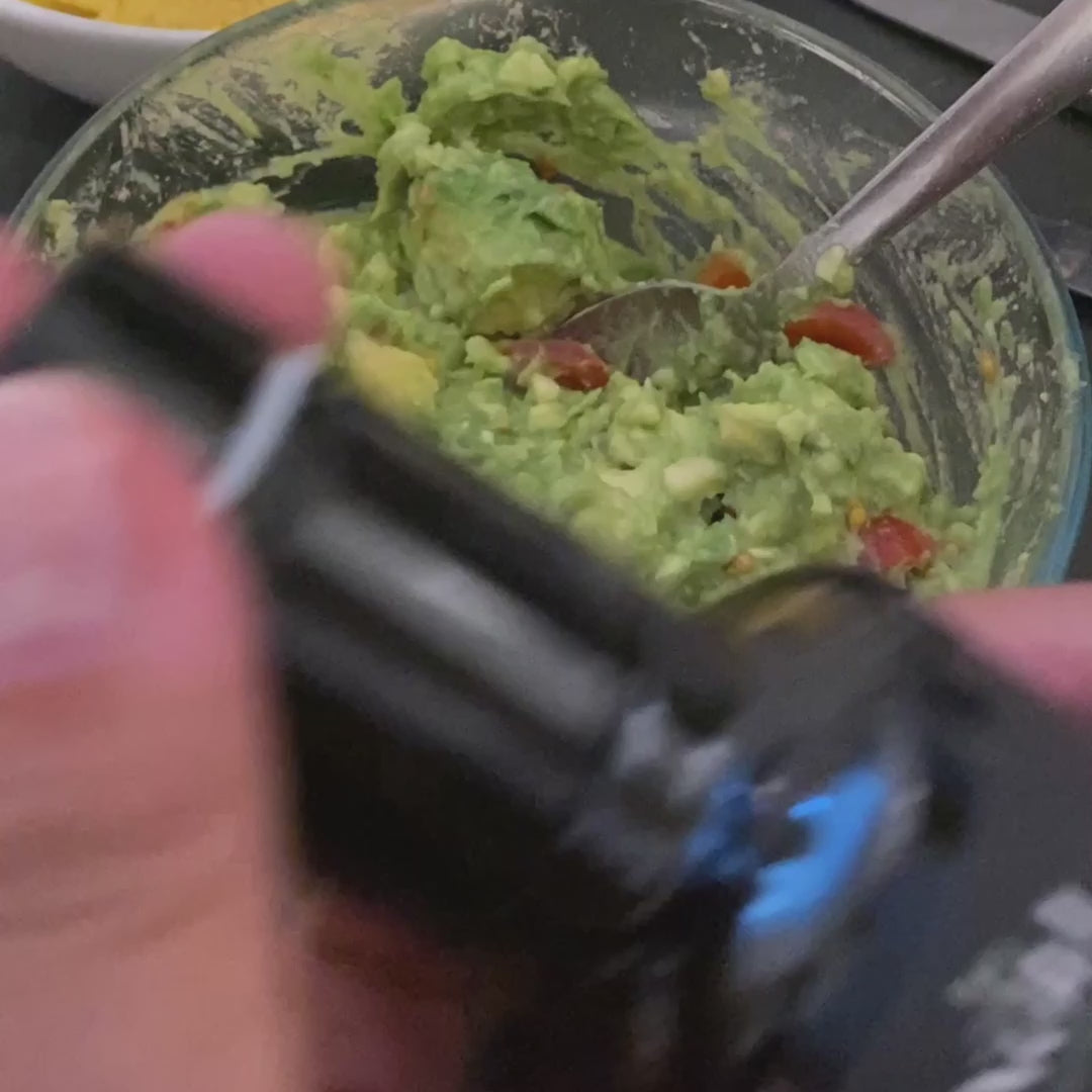 Vignoli Meyer Lemon Infused Extra Virgin Olive Oil front of 8.5oz bottle pouring into guacamole