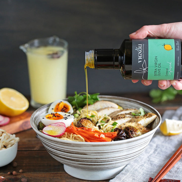 Vignoli Lemon Infused Extra Virgin Olive Oil front of 8.5oz bottle pouring over ramen bowl