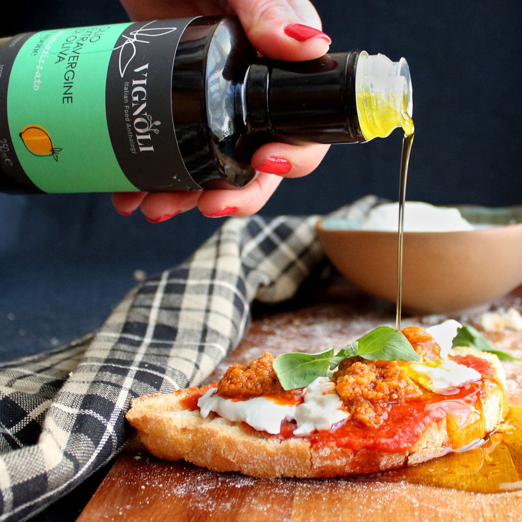 Vignoli Lemon Infused Extra Virgin Olive Oil front of 8.5oz bottle pouring over bruschetta