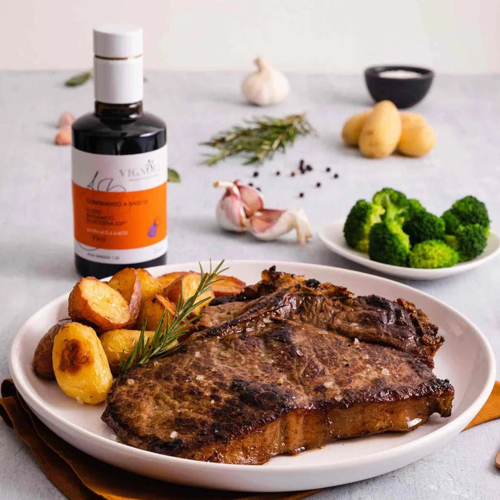 Vignoli Fig Infused Balsamic Vinegar front of 8.5oz bottle with steak, potatoes and broccoli on table