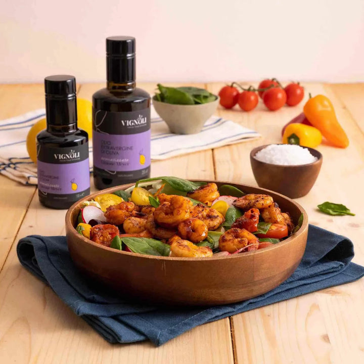 Vignoli Meyer Lemon Infused Extra Virgin Olive Oil front of 8.5oz bottle on kitchen table with shrimp salad in a wooden bowl